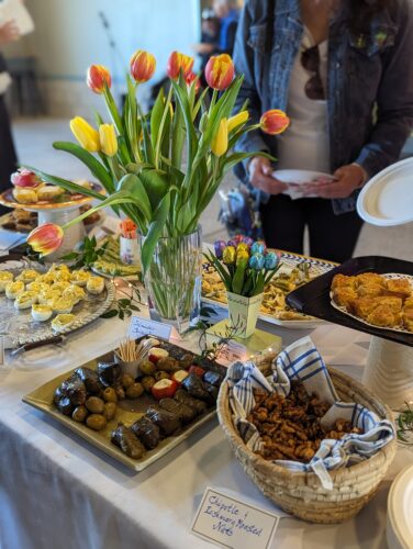 a bouquet of tulips amid appetizers and desserts arranged on a white table